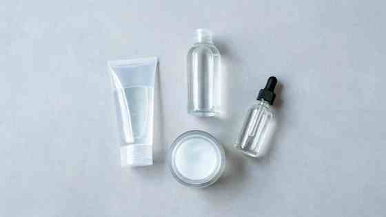Flat lay of lightweight Korean skincare products — gel cleanser, toner, niacinamide serum, and gel moisturizer — on a cool grey surface