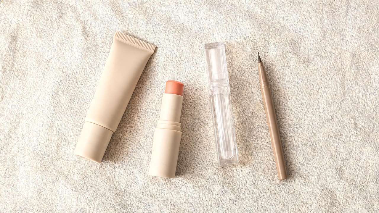 Korean no-makeup makeup products flat lay with BB cream, peachy cream blush, clear lip gloss and a fine brow pencil